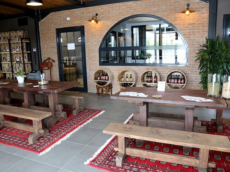 Pineios Brewery tasting room with wood tables with benches and red carpets